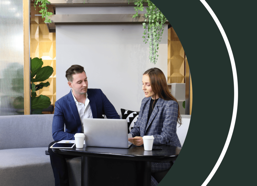 Two procurement professionals reviewing trusted supplier data on a laptop during a strategy meeting.