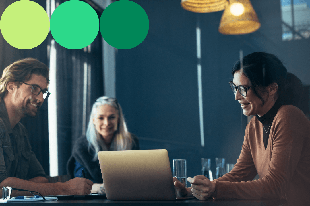 Three professionals collaborating around a laptop in a modern office setting, with green branded circle graphics overlaid in the top left corner.
