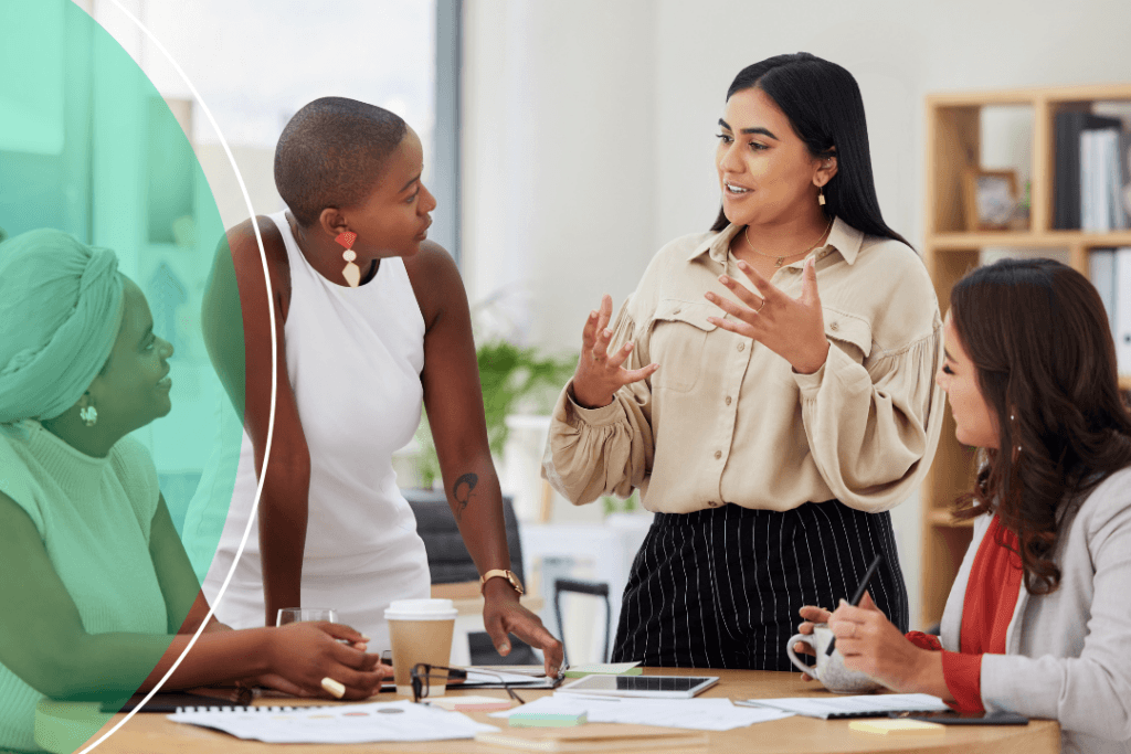 Four women engaged in an active discussion during a workplace meeting, with a green branded circle graphic overlaid on the left side of the image.