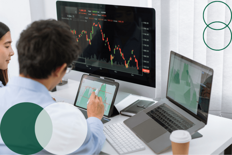 Two professionals analyzing data charts across multiple screens and a tablet in a modern office setting, with dark green and white branded circle graphics overlaid in the corners of the image.