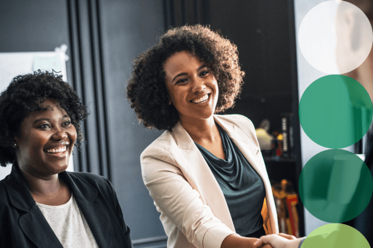 Two businesswomen smiling during a professional meeting or handshake, representing supplier partnership and collaboration.