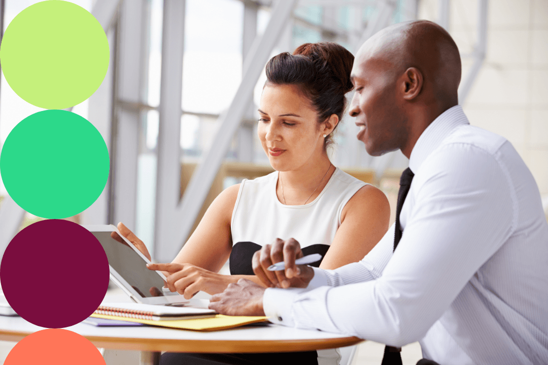 Two procurement professionals reviewing supplier diversity data together on a tablet.
