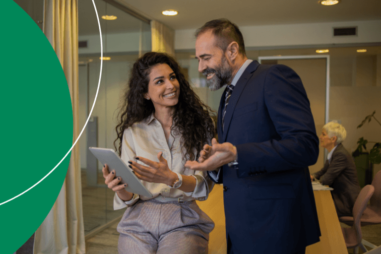Two business professionals reviewing supplier compliance data on a tablet in a modern office setting.