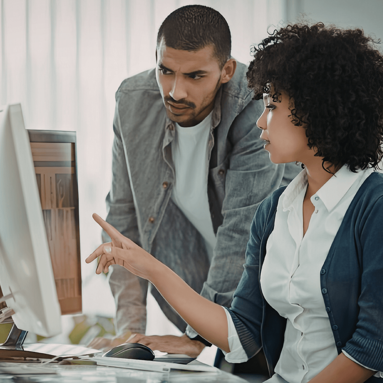 Two colleagues in an office looking at a computer monitor together.