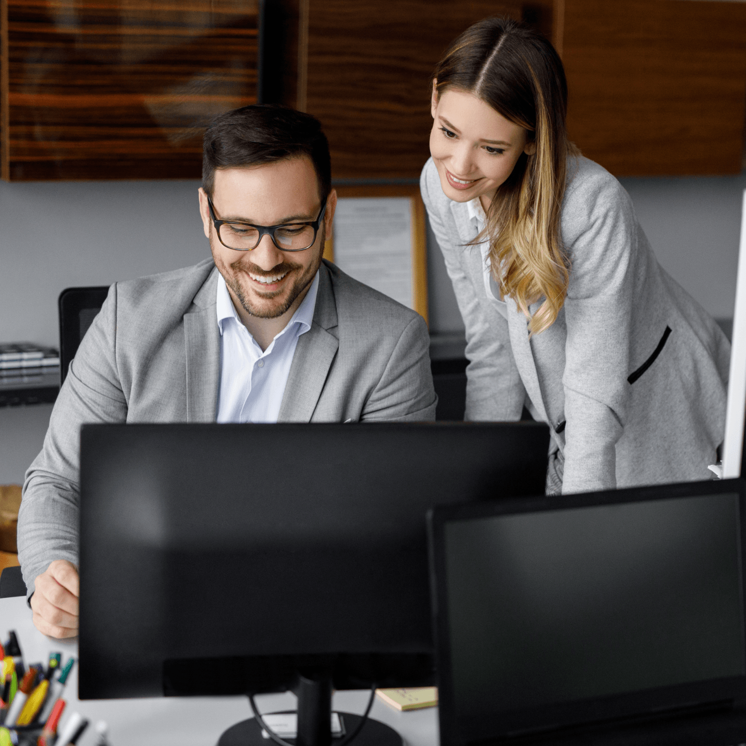Two colleagues reviewing data together at a desktop workstation in an office