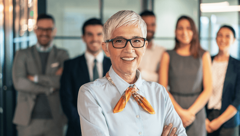 Legal and compliance leader smiling with arms crossed, team members standing behind her in an office setting