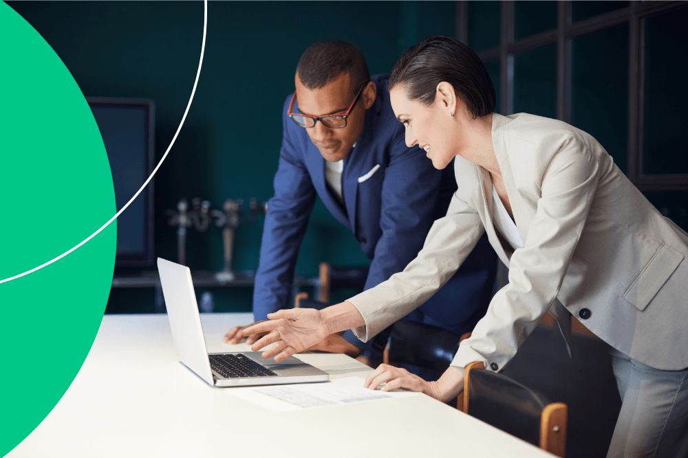 Two colleagues looking at data on their laptop and pointing at the screen