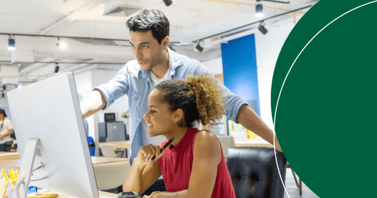 Two procurement professionals reviewing supplier data together at a desktop monitor in an office.