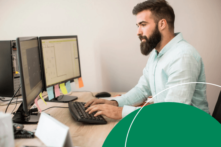 A procurement professional works at a dual-monitor desktop setup, reviewing data on screen.